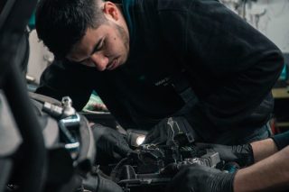 Zwei Männer arbeiten gemeinsam an einem Auto-Motor.