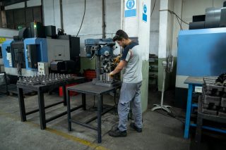 Ein Mann arbeitet in einer Fabrik, umgeben von Maschinen und industriellen Geräten.